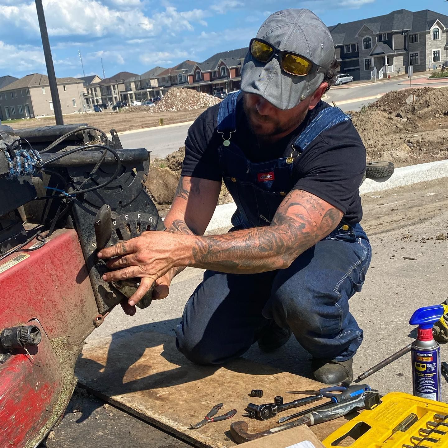 Kneeling at the trailer, repairing equipment with tools laid out on a board